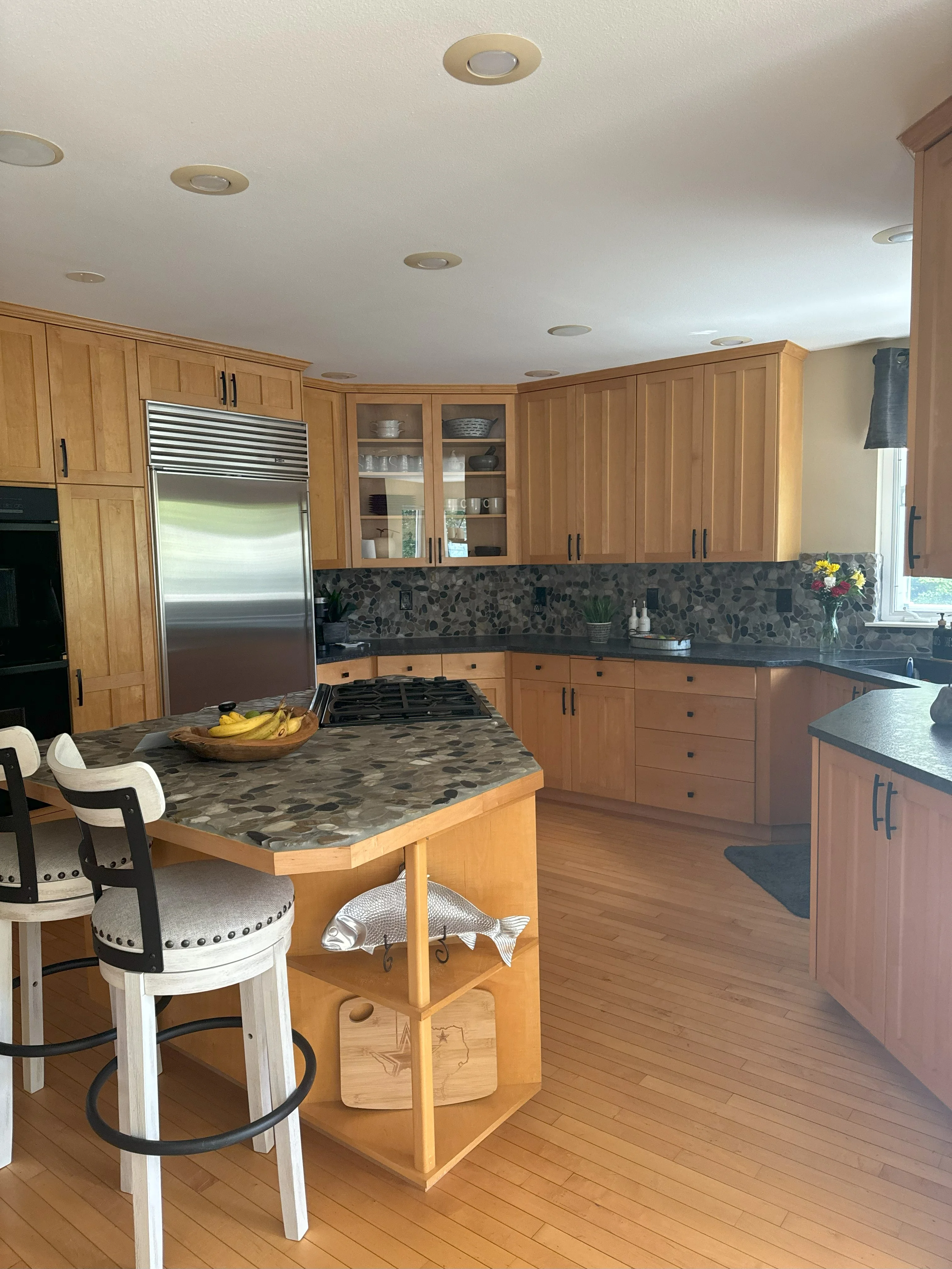 Kitchen with wood cabinetry, granite countertops, stainless steel appliances, and wood island
